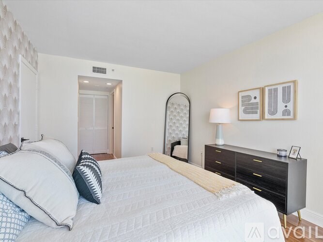 A bedroom with a large bed, a dresser, and a lamp.