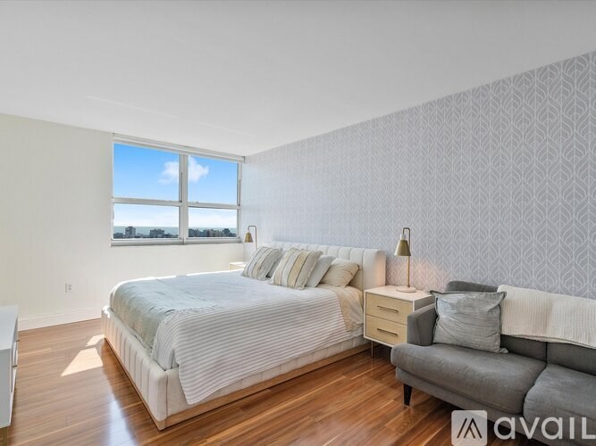 A bedroom with a large bed and a grey couch.