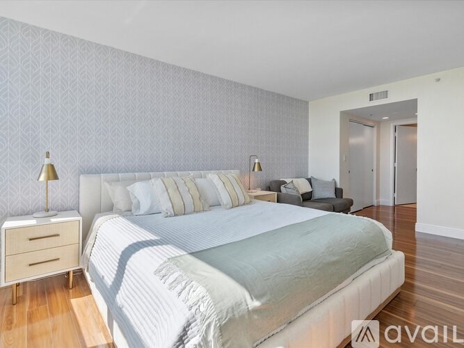 A bedroom with a large bed and a grey couch.