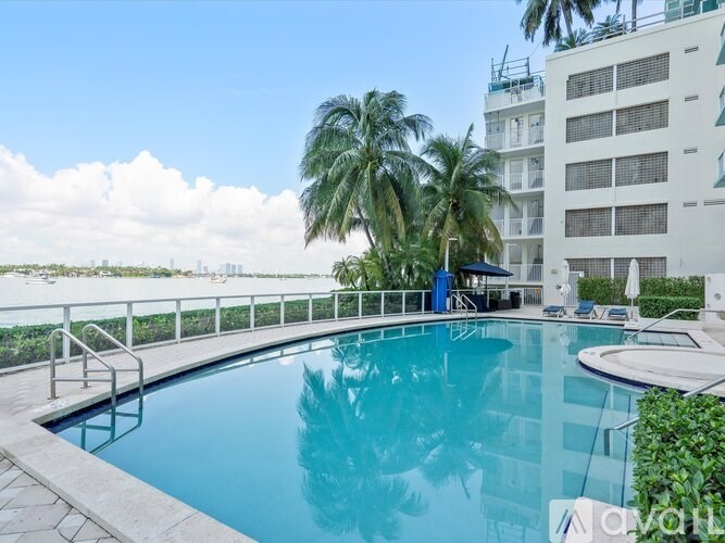 A swimming pool on a balcony with a building and palm trees in the background.