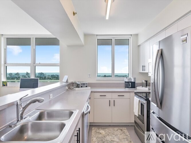 A modern kitchen with stainless steel appliances and a large window.