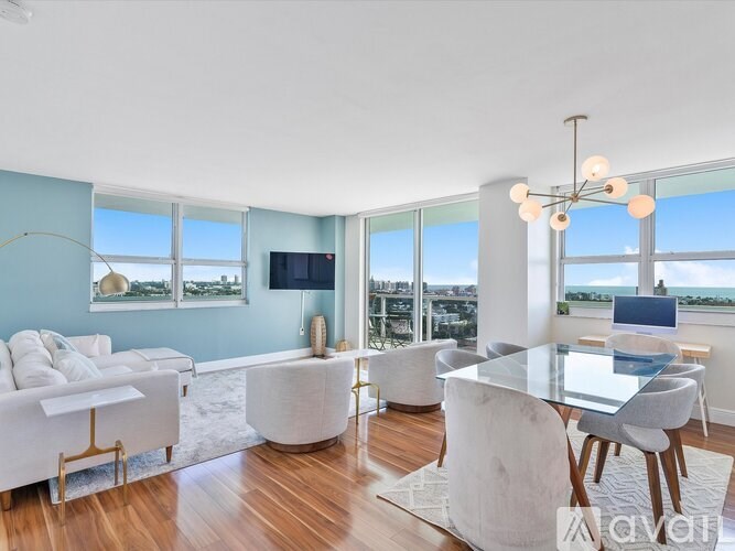 A modern living room with a white sofa, a glass table, and a chandelier.