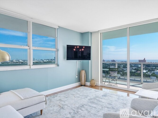 A living room with a flat screen TV and a view of the city.