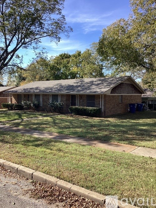 A house with a brown roof and a green lawn in front.