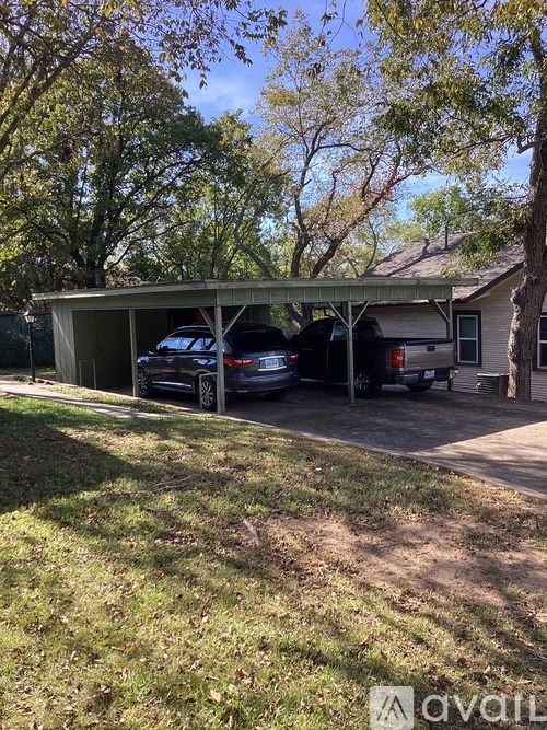 A carport with three cars parked in front of a house.