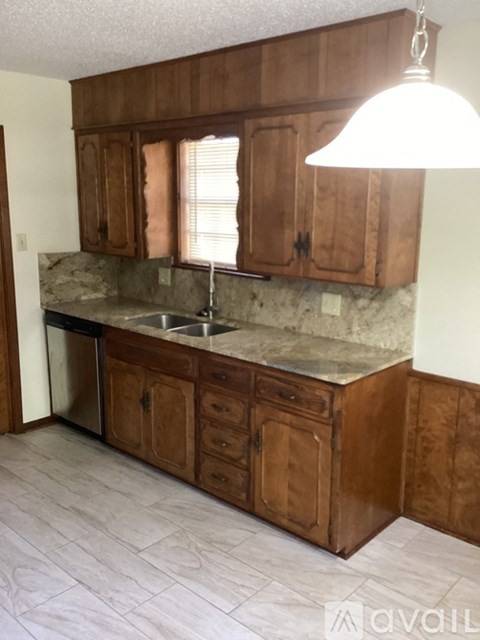 A kitchen with wooden cabinets and a marble countertop.