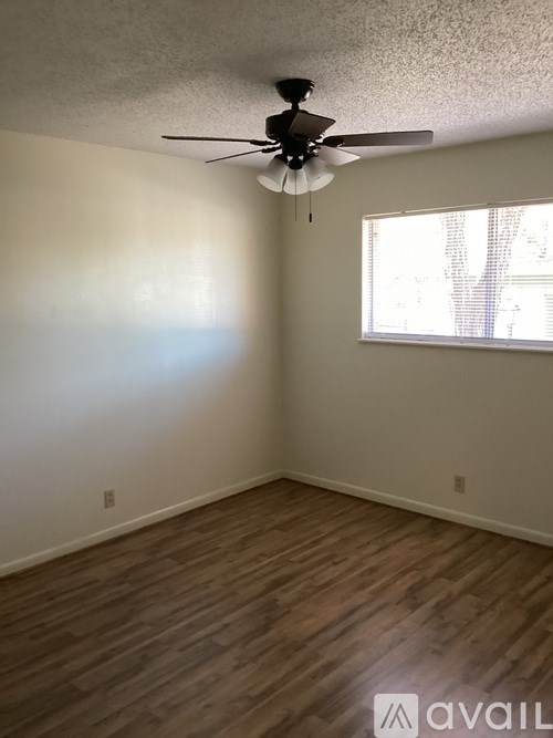A room with a ceiling fan and wooden flooring.