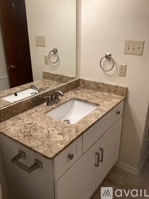 A bathroom with a granite countertop and a sink.