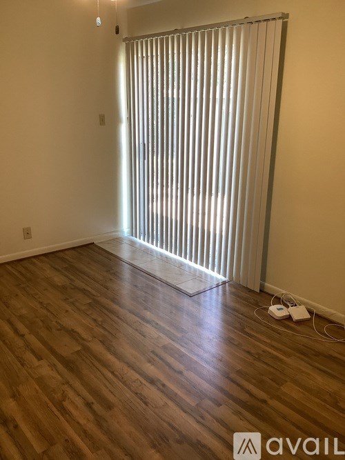 A room with wooden flooring and a white blind on the window.