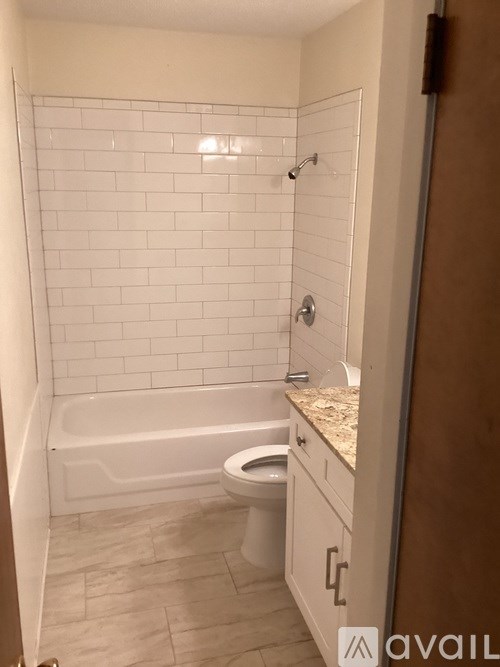 A white tiled bathroom with a bathtub, toilet, and sink.
