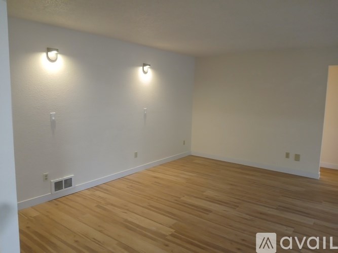 A room with wooden flooring and two wall lights.