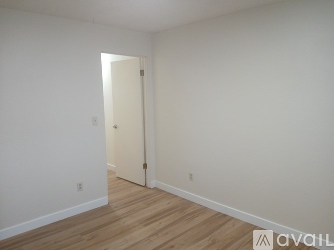 A room with a white door and wooden floor.