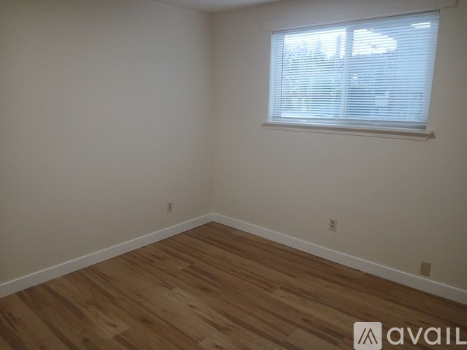 A room with wooden flooring and a window with blinds.