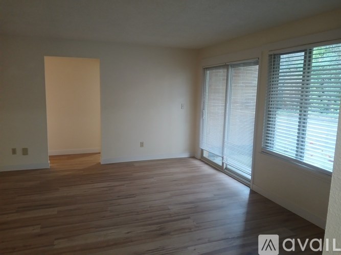 A room with wooden flooring and a window with blinds.