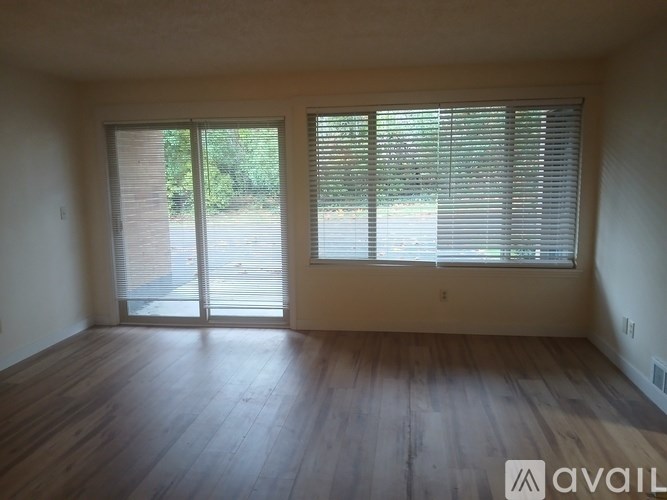 A room with wooden floors and a large window with blinds.