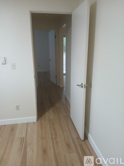 A hallway with a door on the right and a light switch on the wall.