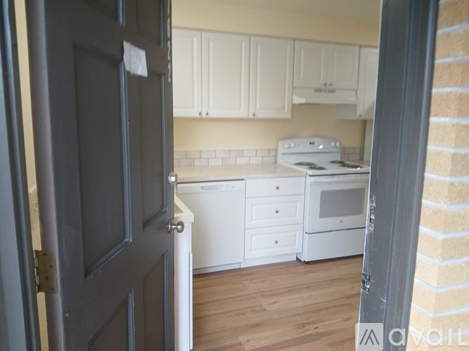 A kitchen with white appliances and wooden floors.