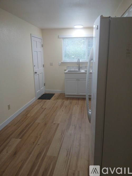 A kitchen with a white refrigerator and wooden floors.