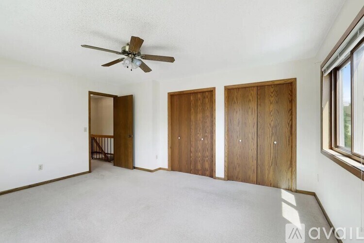 A room with a ceiling fan and three wooden doors.