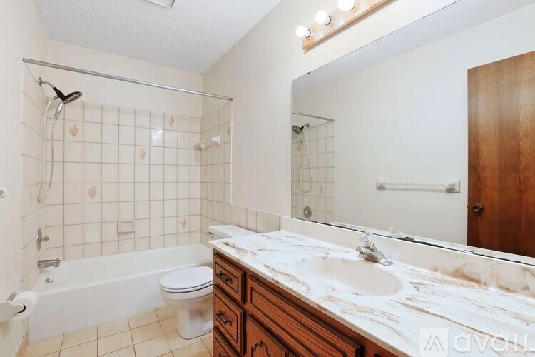 A bathroom with a white tub, sink, and tiled walls.