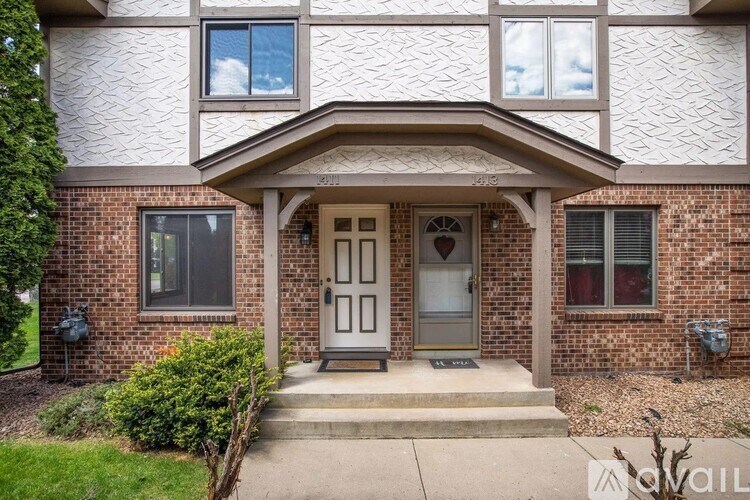 A house with a grey front door and a brick wall.