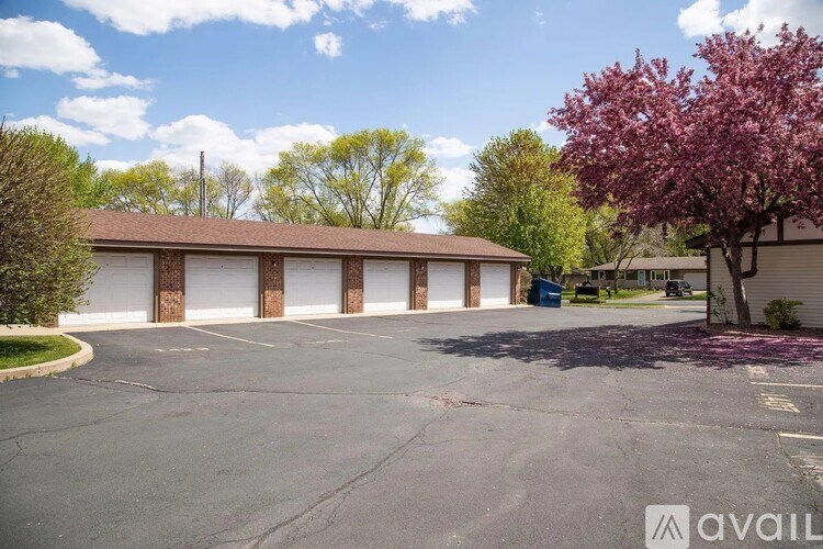 A parking lot with a building and a tree with purple leaves.