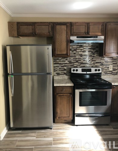 A stainless steel refrigerator and oven in a kitchen with wooden cabinets.