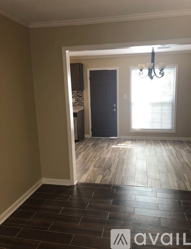 A room with a dark wood floor and a chandelier.