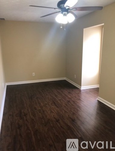 A room with a ceiling fan and wooden flooring.