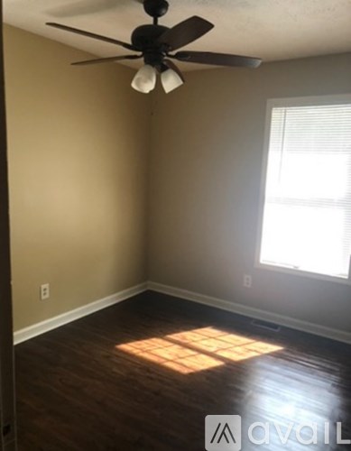 A room with a ceiling fan and a window letting in sunlight.
