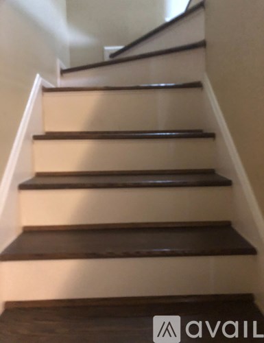 A staircase with brown steps and a black handrail.