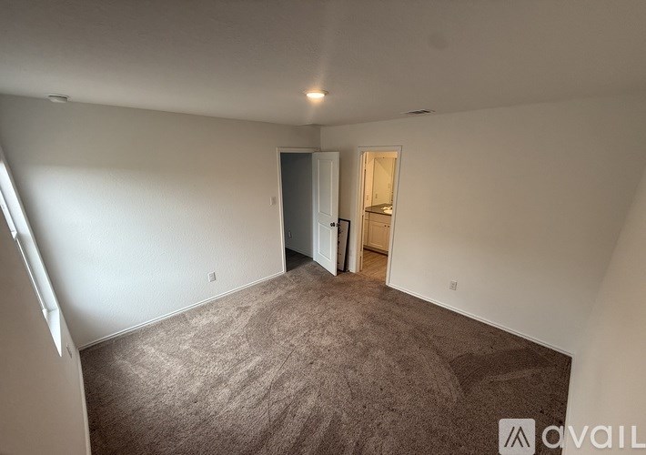 A room with carpeted floor and a doorway leading to another room.