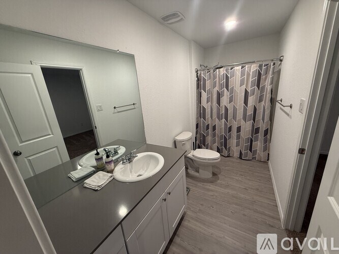 A bathroom with a sink, mirror, toilet and shower.
