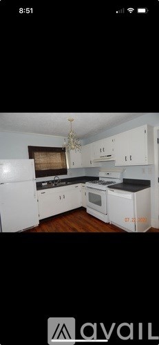 A kitchen with white cabinets and a black countertop.