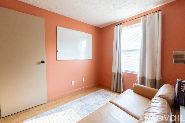 A living room with a couch and a whiteboard on the wall.