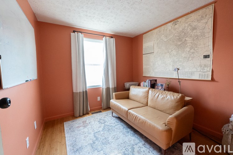 A living room with a tan couch and a map on the wall.