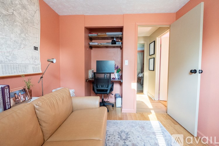 A living room with a tan couch and a map on the wall.