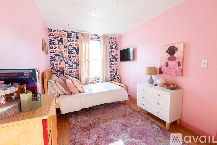 A bedroom with pink walls and a bed with a white comforter.