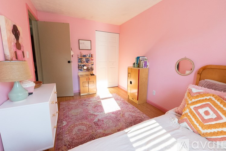 A bedroom with pink walls and a white bed.