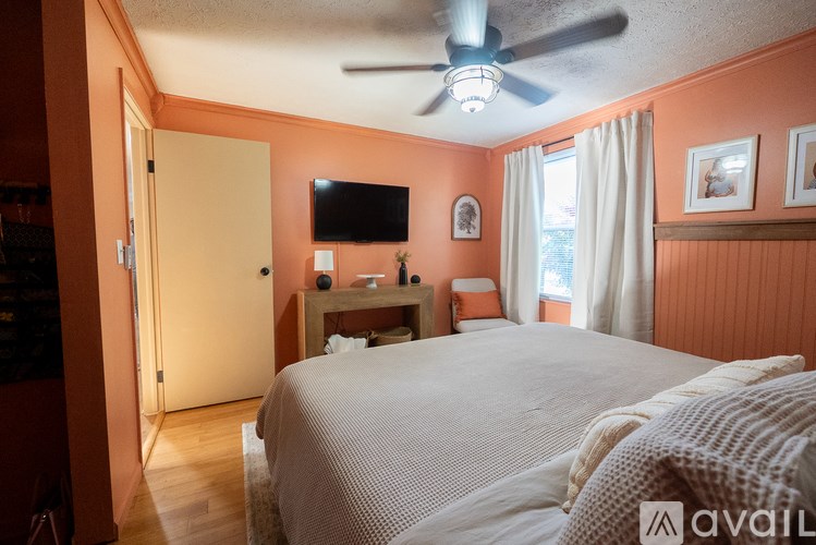 A bedroom with a bed, a ceiling fan, and a television on the wall.