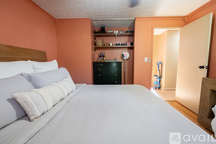 A bedroom with a bed, nightstand, and a clock on the wall.