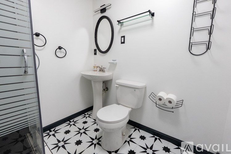 A white toilet sits in a bathroom with black and white tile flooring and walls.