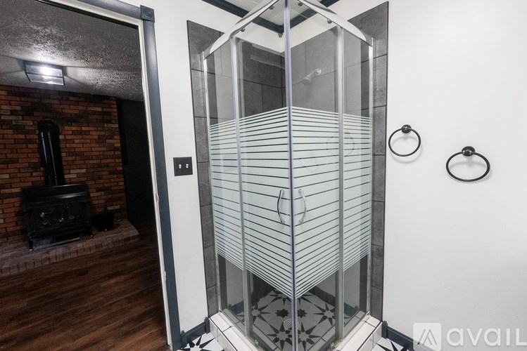 A bathroom with a glass shower stall and a brick fireplace.