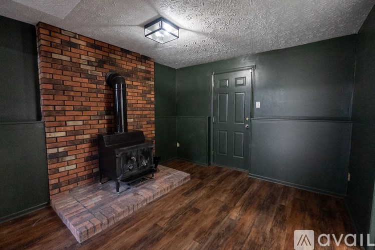 A room with a wood burning stove and a brick wall.
