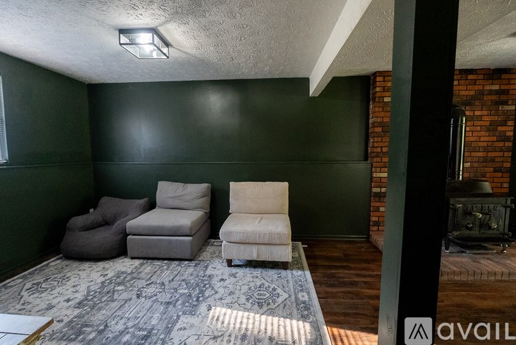 A living room with a grey rug and three chairs.