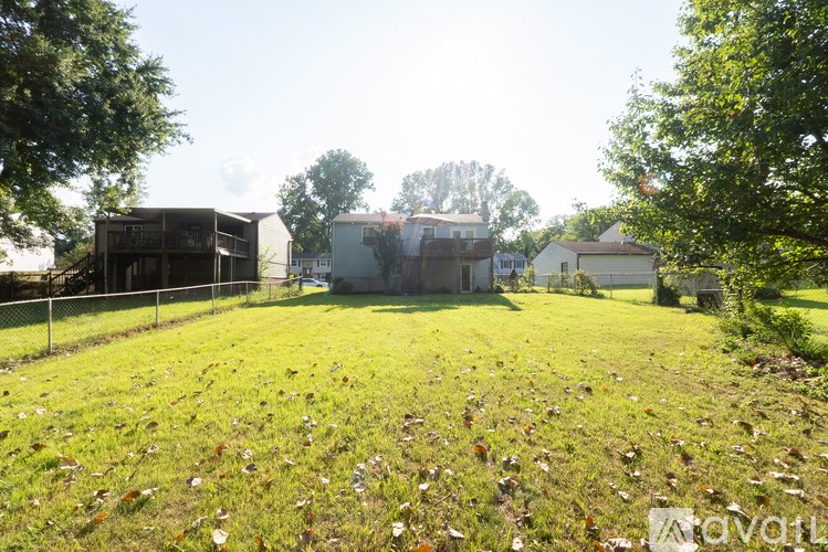 A grassy field with trees and buildings in the background.