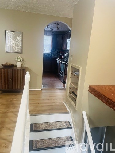 A hallway with a staircase leading to a kitchen.