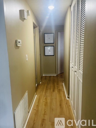 A long hallway with wood floors and white walls.