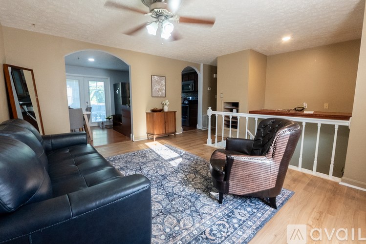A living room with a black leather couch and a patterned rug.