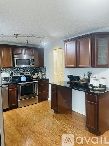 A kitchen with dark wood cabinets and a black countertop.